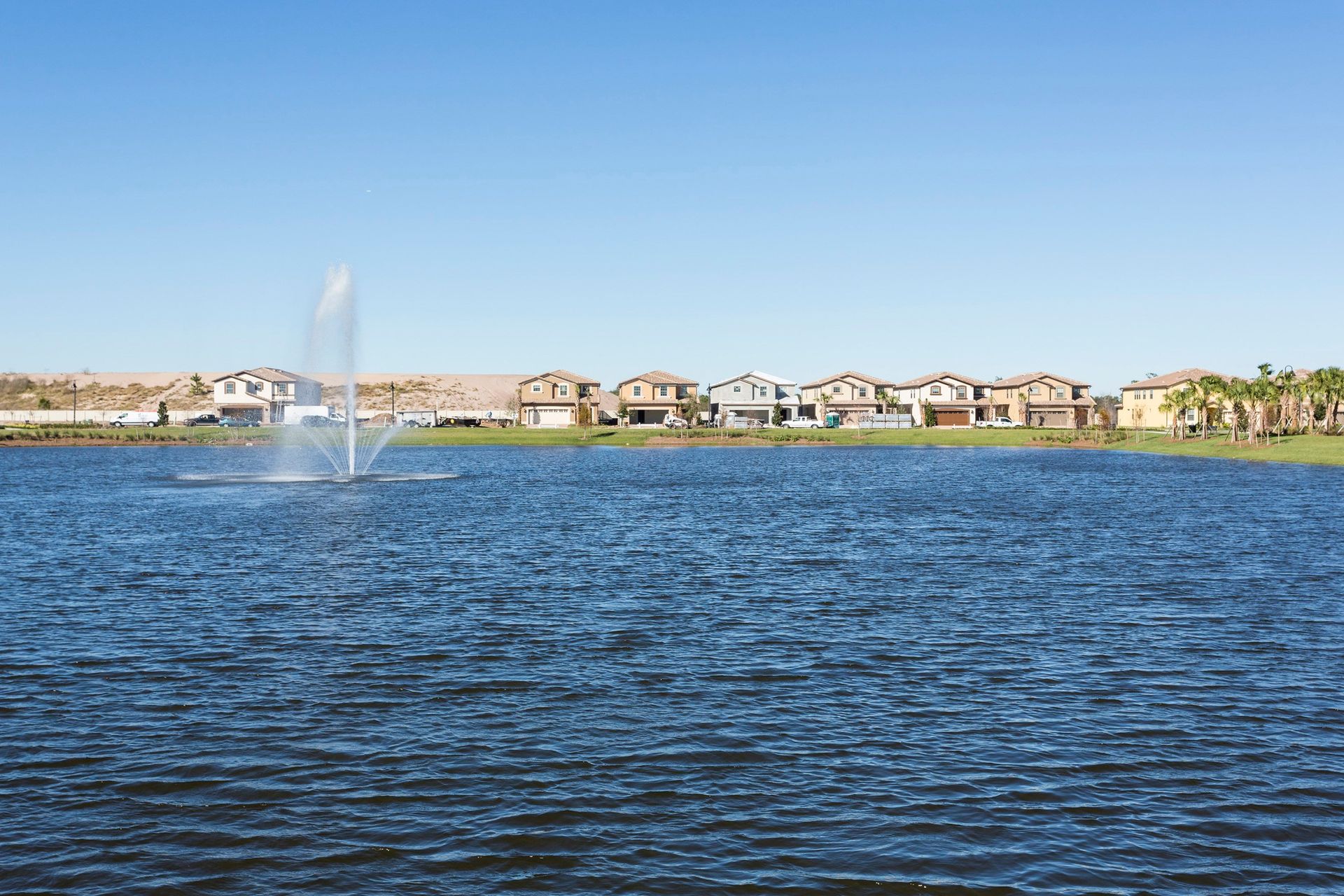 Tranquil lake view with a central fountain and nearby homes