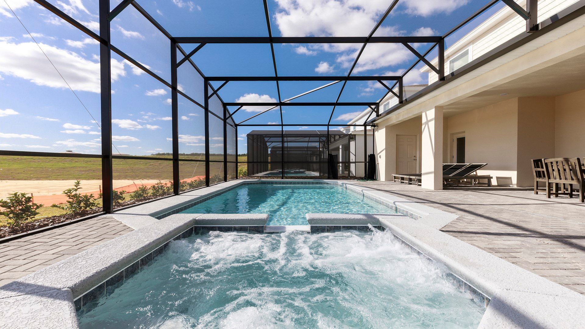 Private screened-in pool and spa with open views, lounge chairs, and dining area.