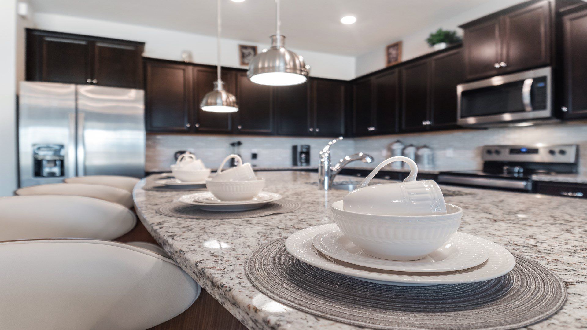 Elegant kitchen with granite countertops, dark cabinets, and modern decor.