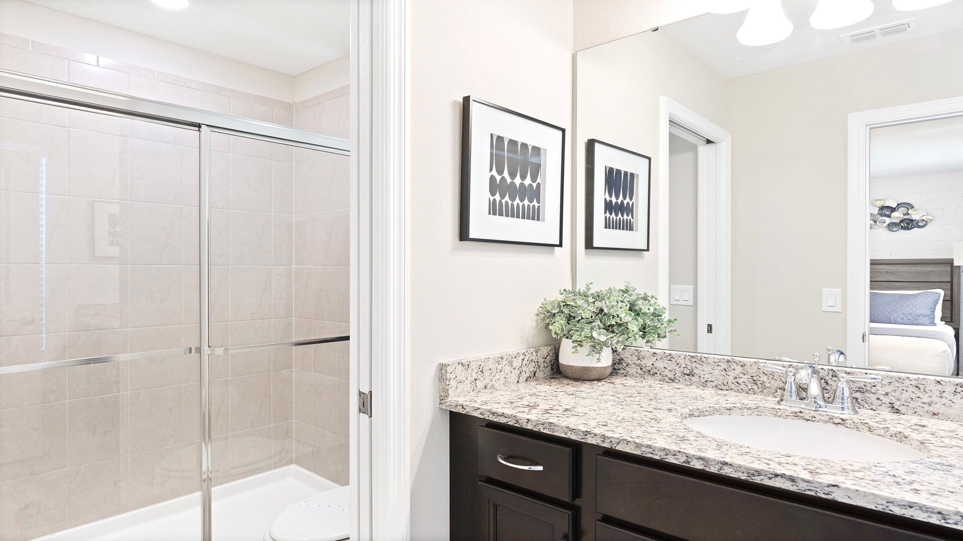 Modern bathroom with a granite vanity, glass-enclosed shower, and minimalist decor.