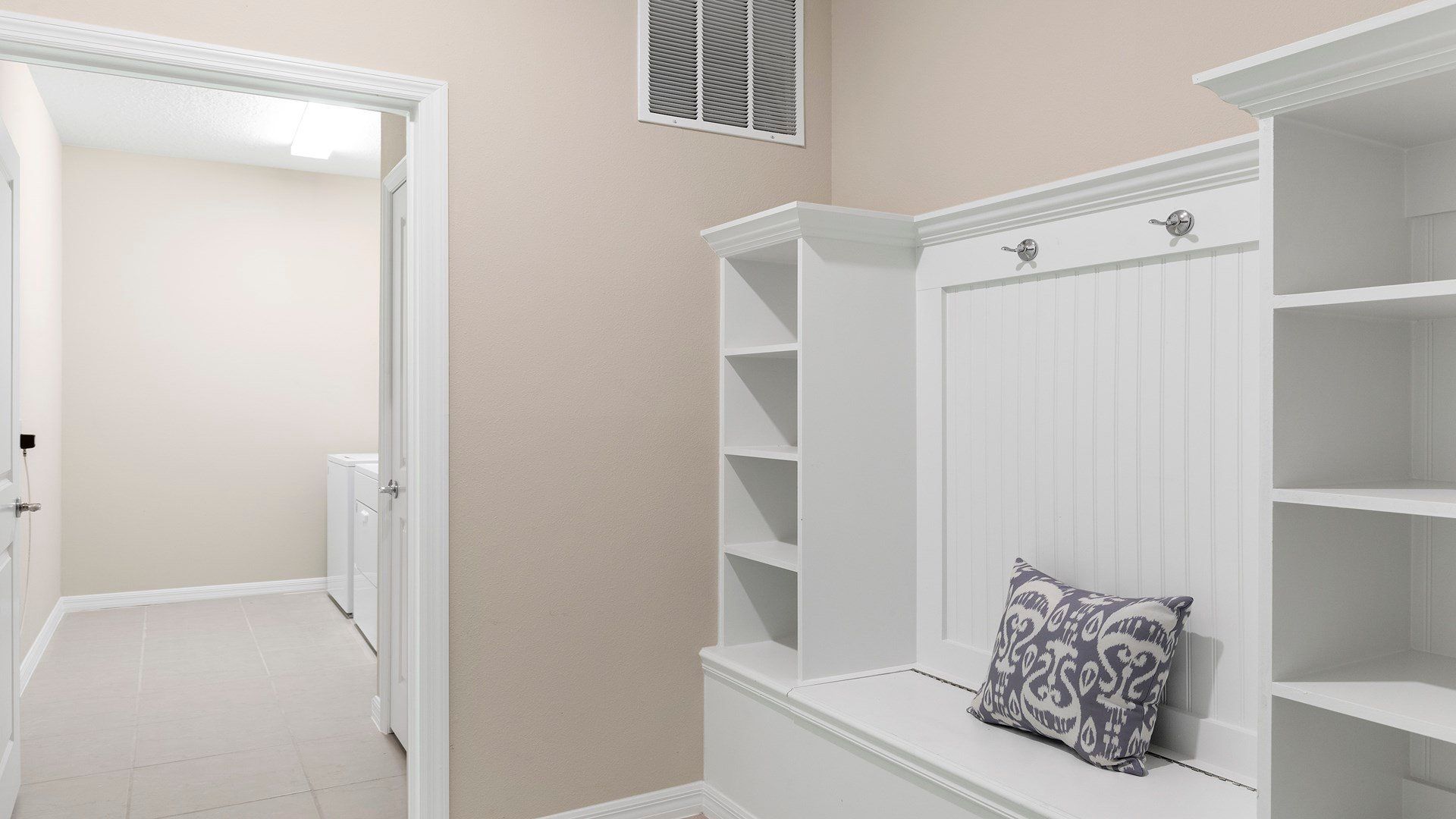 Functional mudroom with built-in shelves, seating, and access to the laundry room.