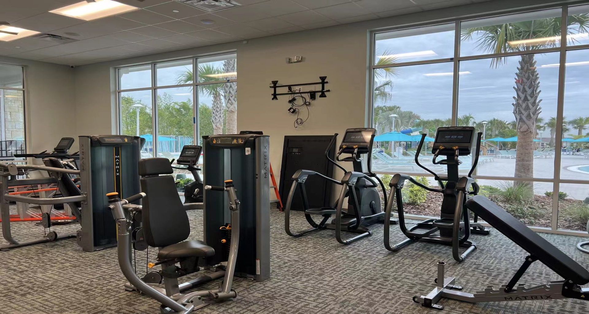 Bright gym with advanced equipment and floor-to-ceiling windows overlooking the pool!