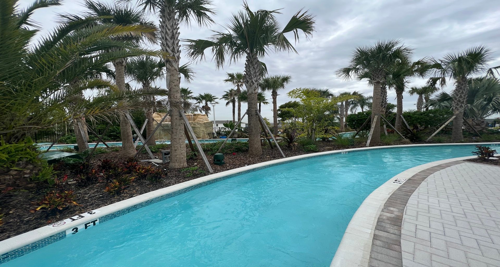 Exciting water slides tower over a serene pool, offering fun amidst lush palm trees.