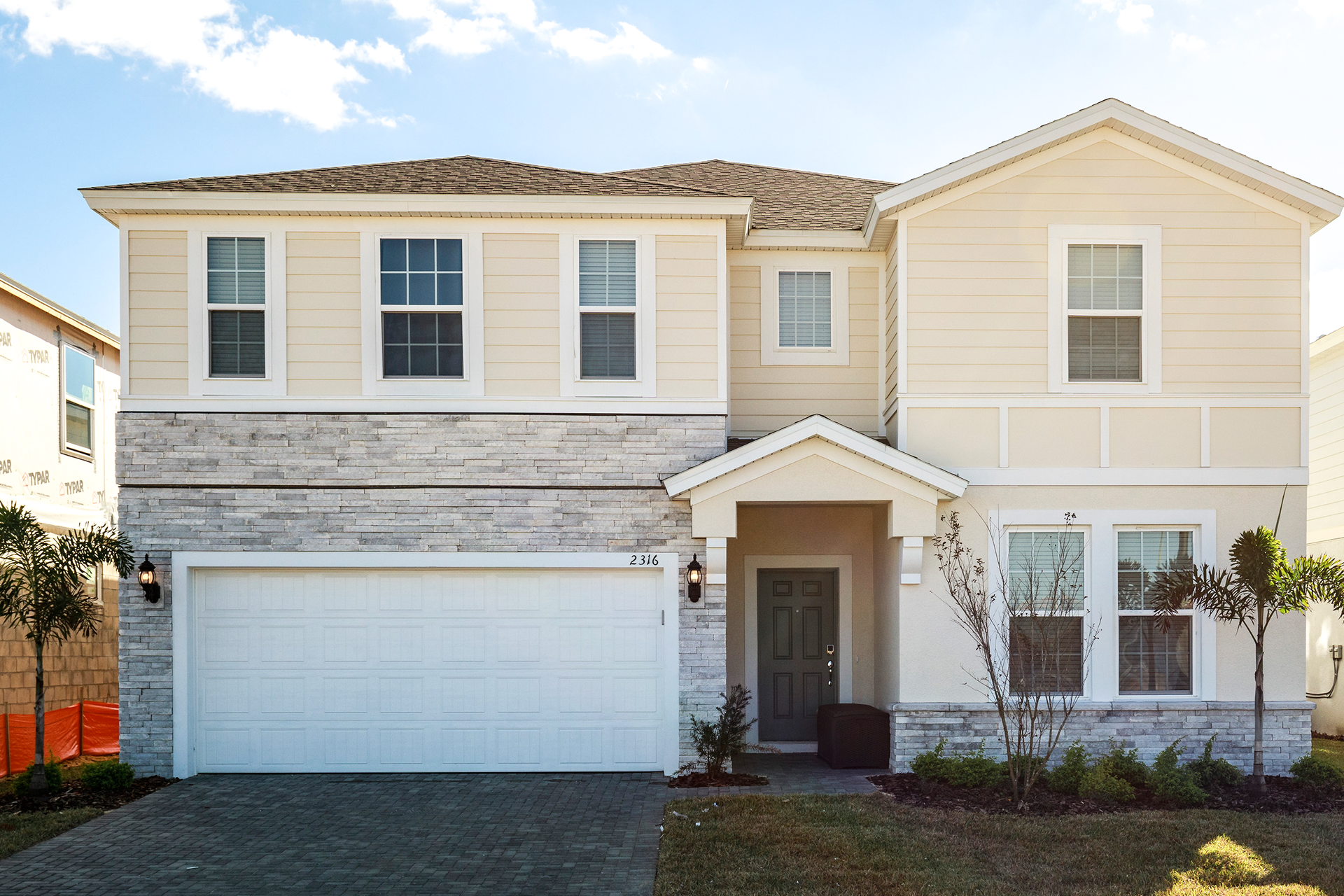 Beautiful two-story modern home with a stone facade, manicured lawn, and garage.