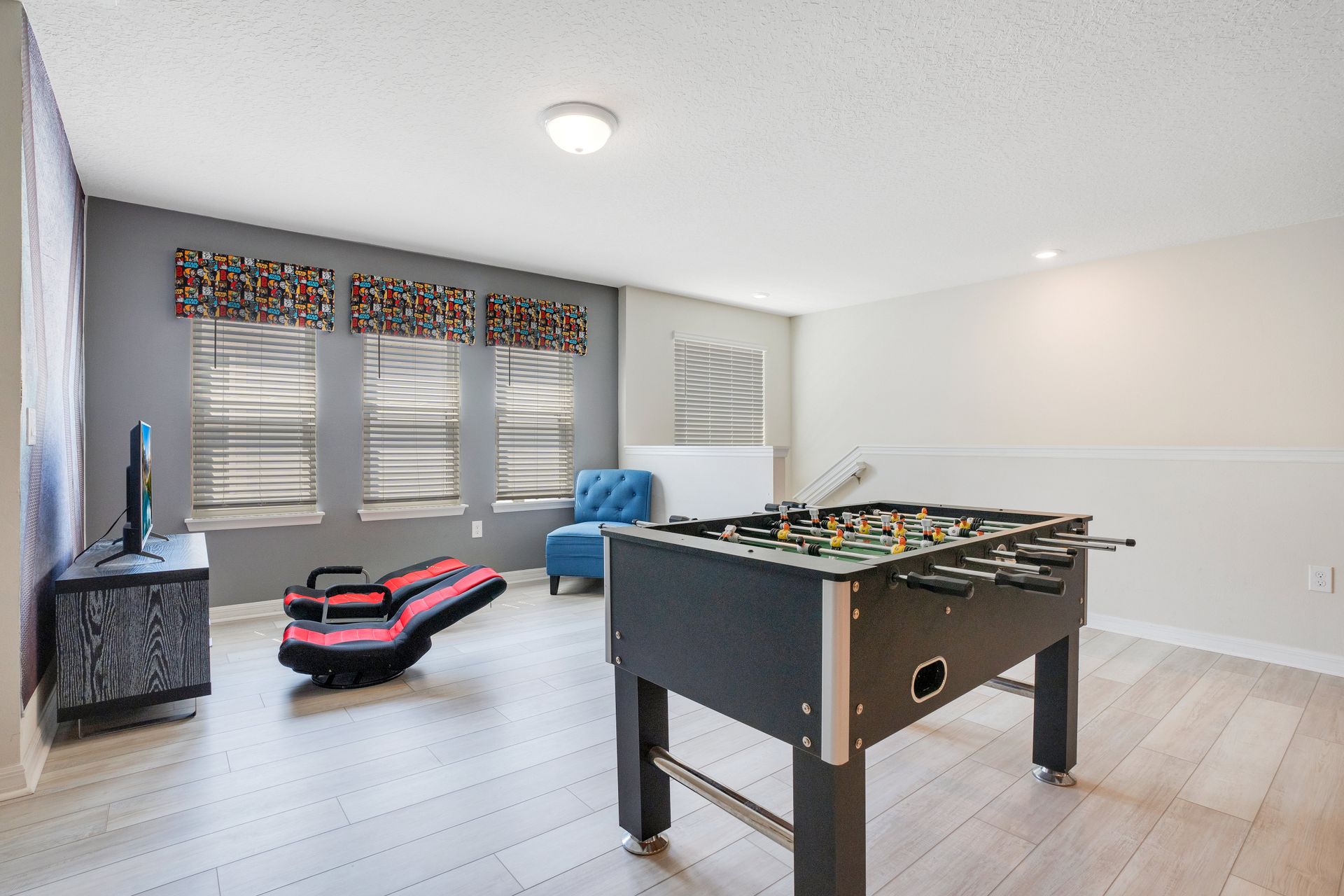 Bright game room featuring a foosball table, gaming chairs, and a cozy lounge area.