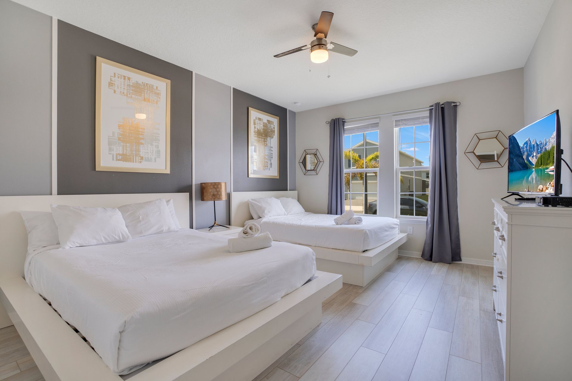 Bright bedroom with two modern platform beds, sleek decor, and large windows.