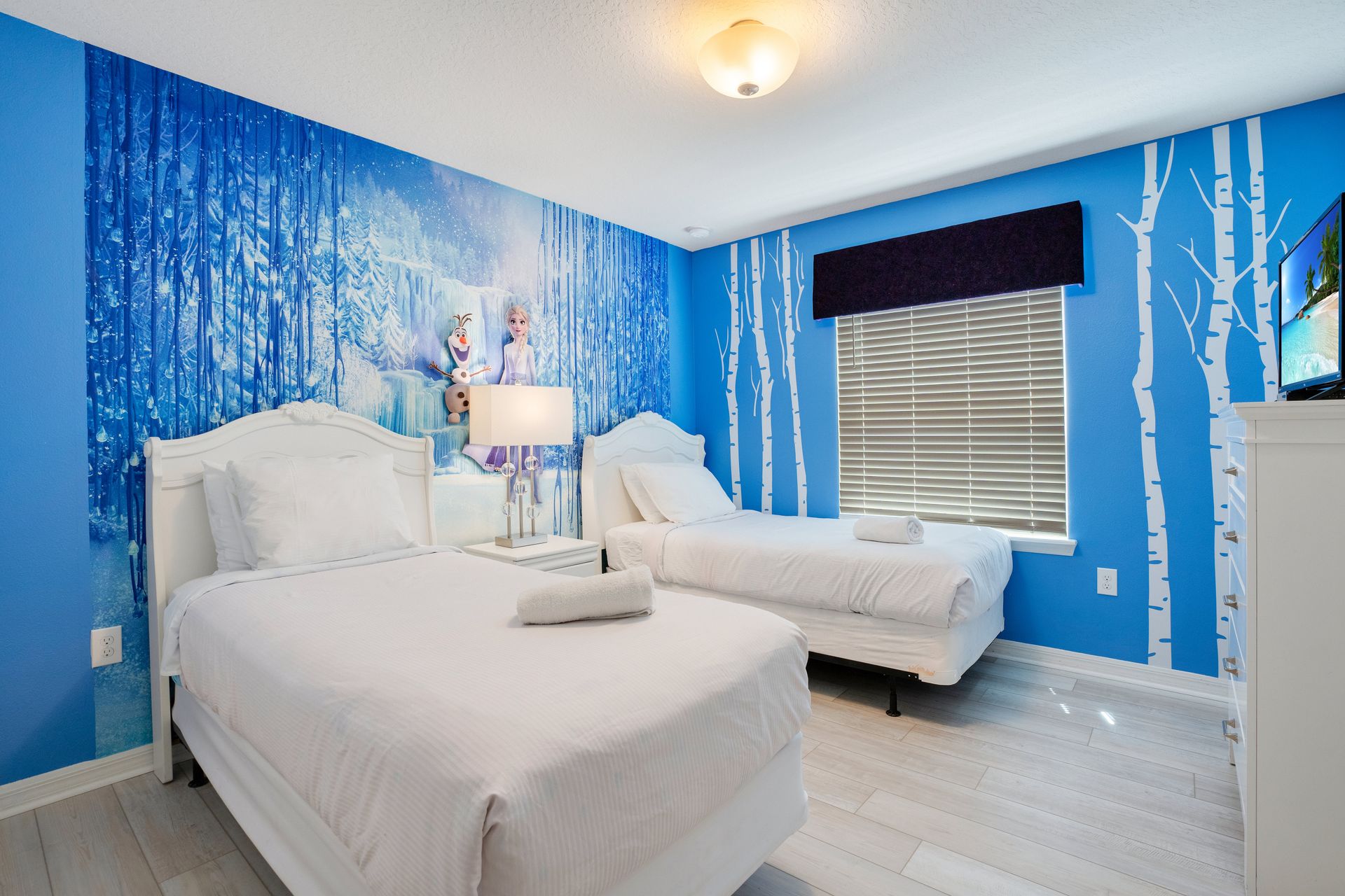 Frozen-themed bedroom with twin beds, icy blue murals, and whimsical decor.