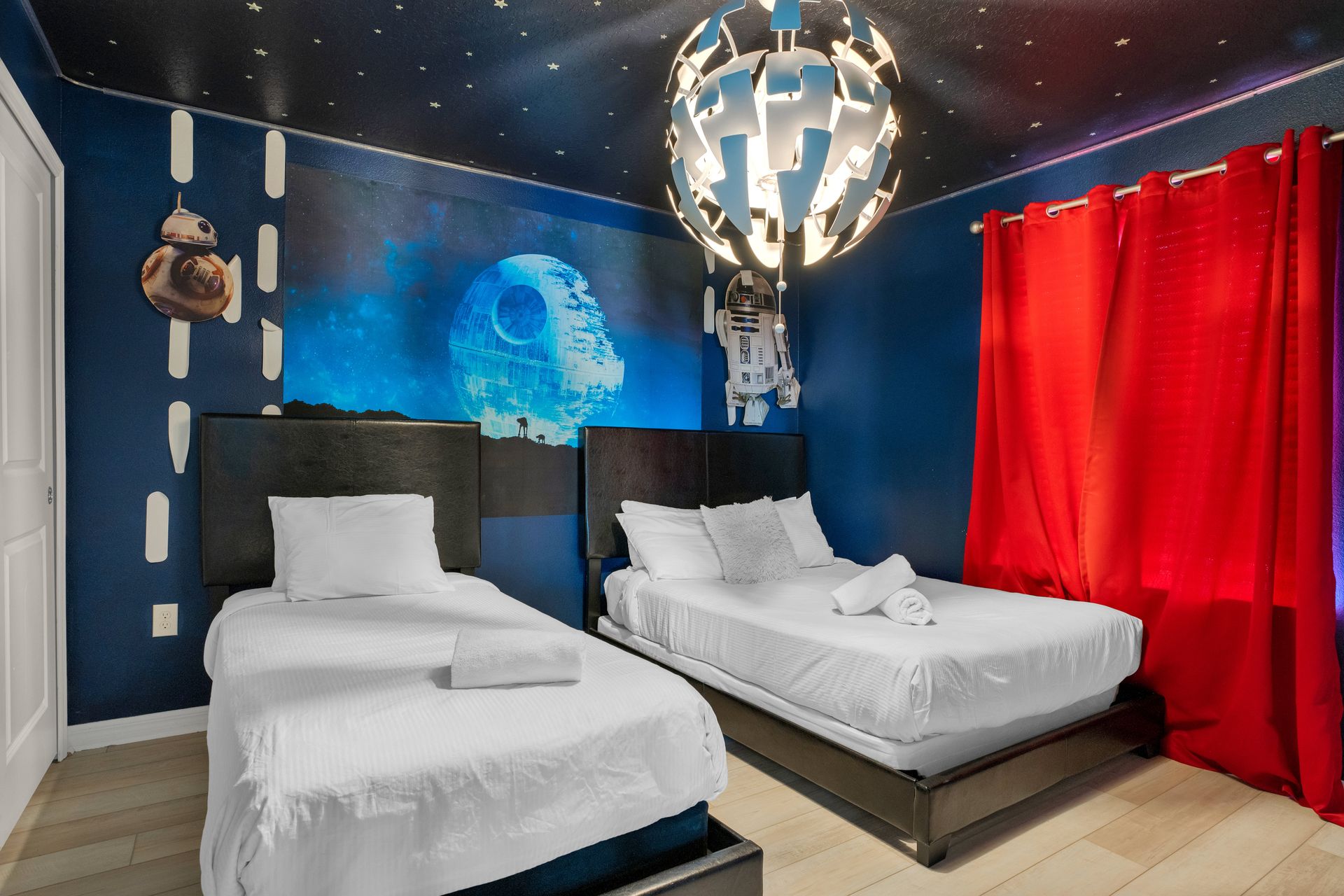 Star Wars-themed bedroom with twin beds, galactic murals, and bold red curtains.