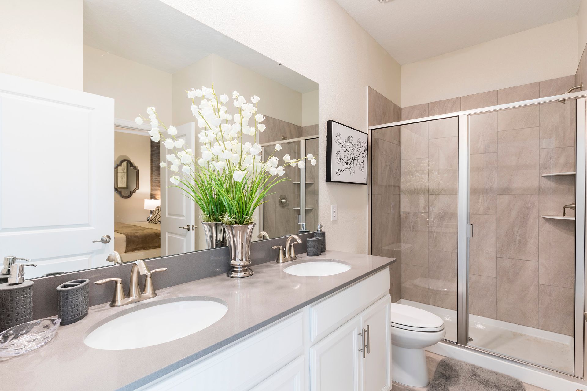 Elegant bathroom with dual sinks, glass shower, and chic floral accents.