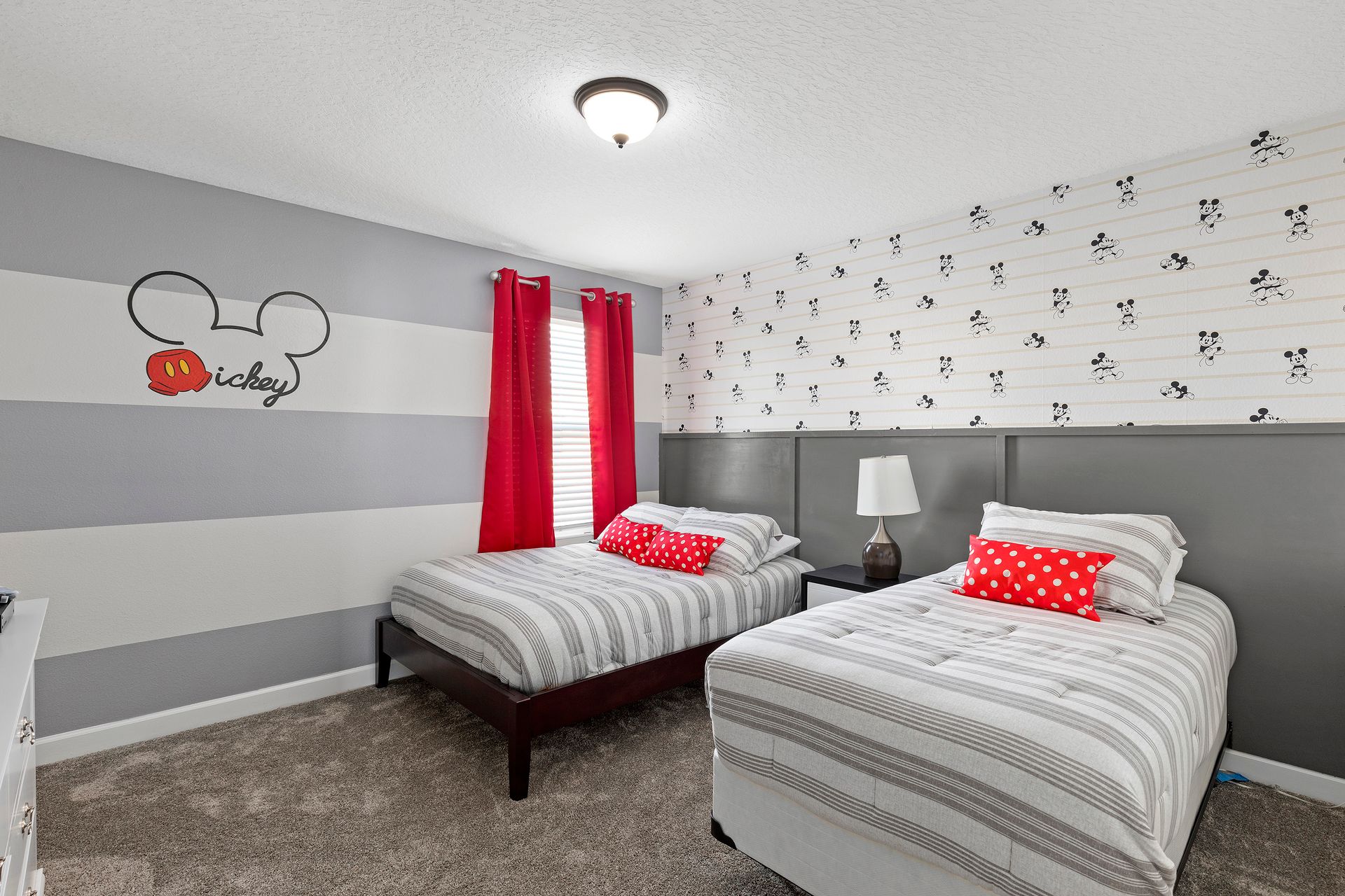 Mickey-themed room with playful decor, twin beds, and bright red accents.