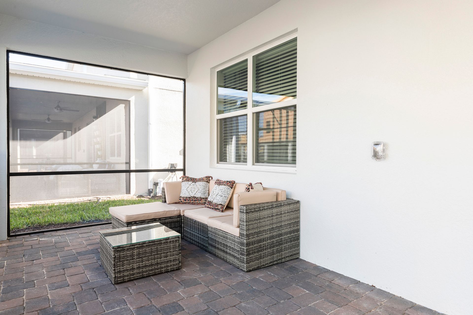 Cozy screened-in patio with wicker seating, soft cushions, and garden views.