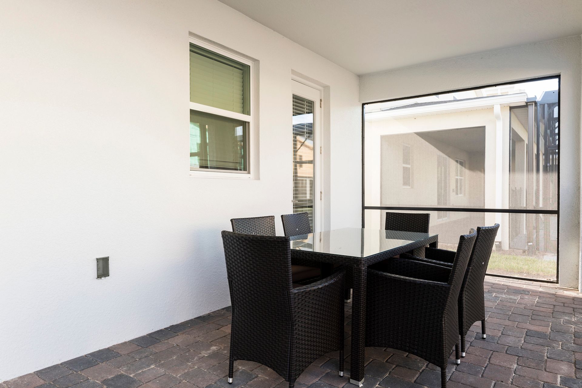 Cozy screened-in patio with wicker seating, soft cushions, and garden views.