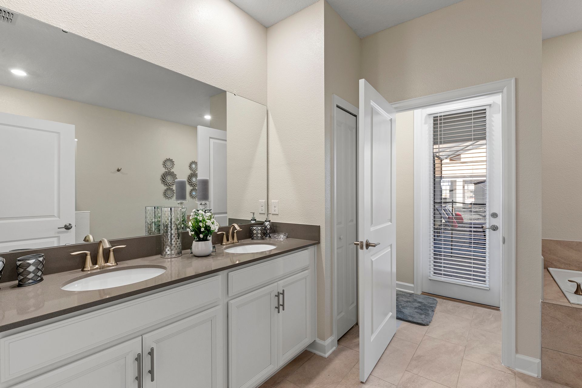 Elegant bathroom with dual sinks, gold fixtures, and patio access.