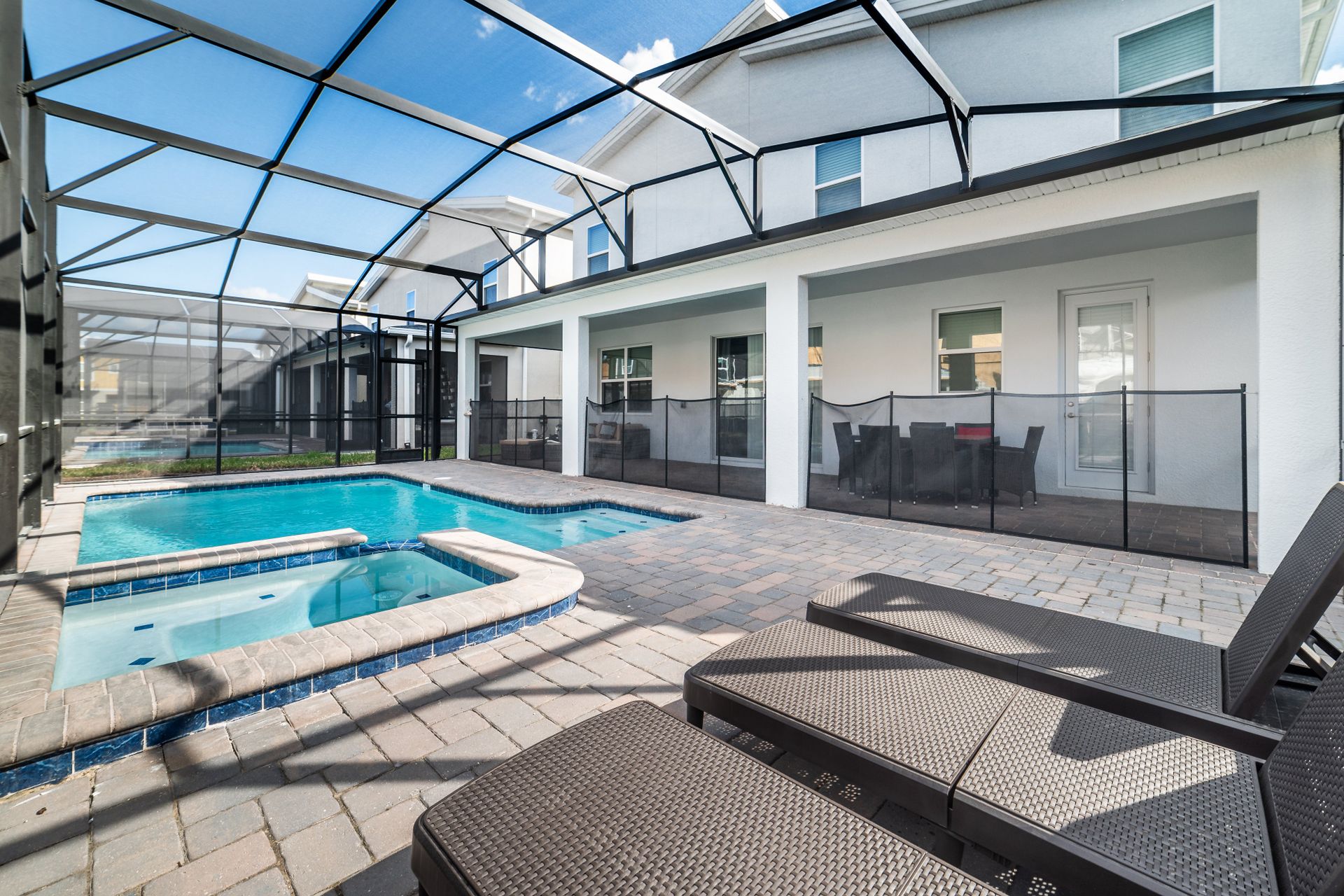 Screened-in patio with a private pool, hot tub, and cozy lounge seating.