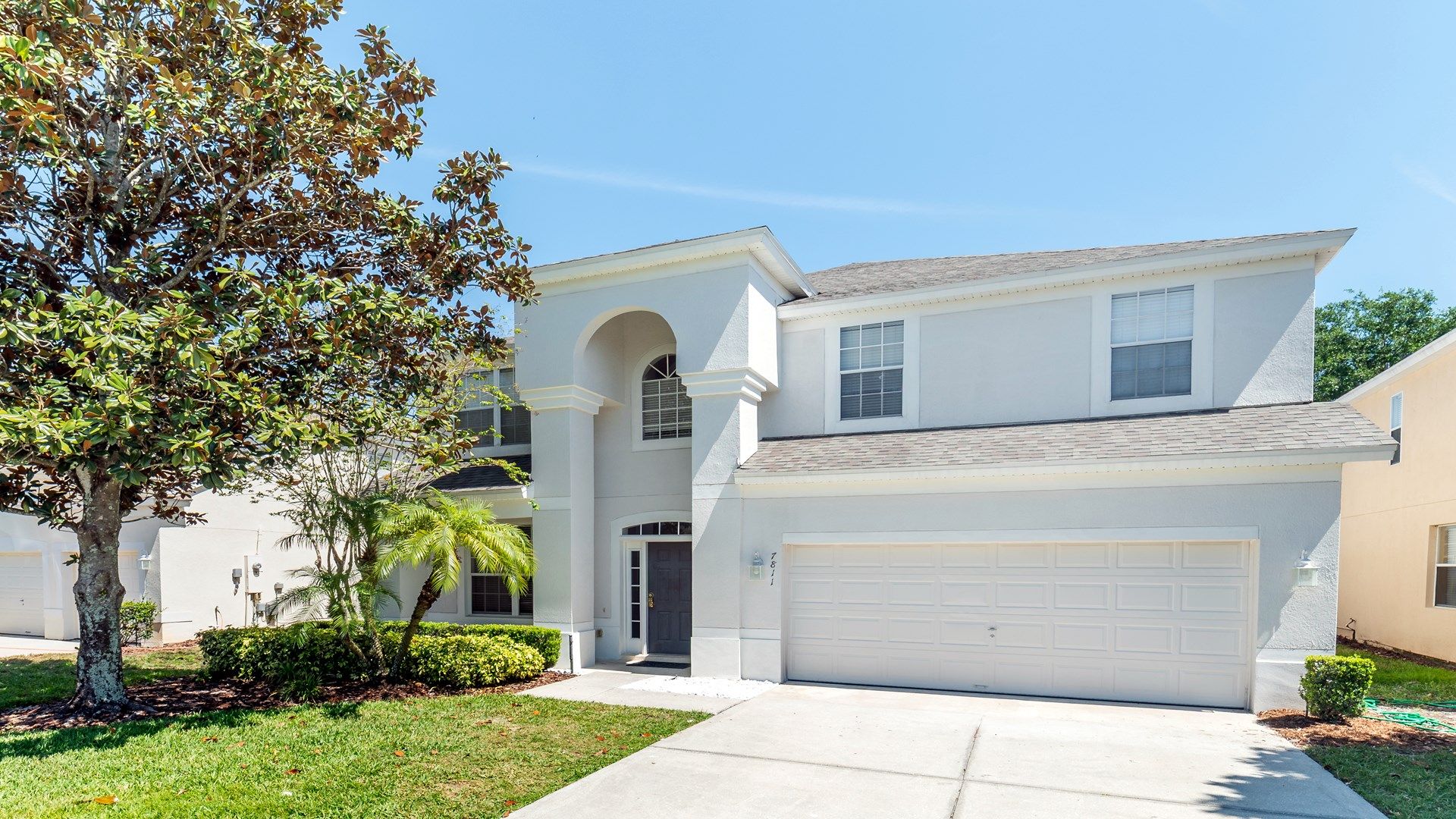 Elegant two-story home with a grand entryway and lush landscaping.