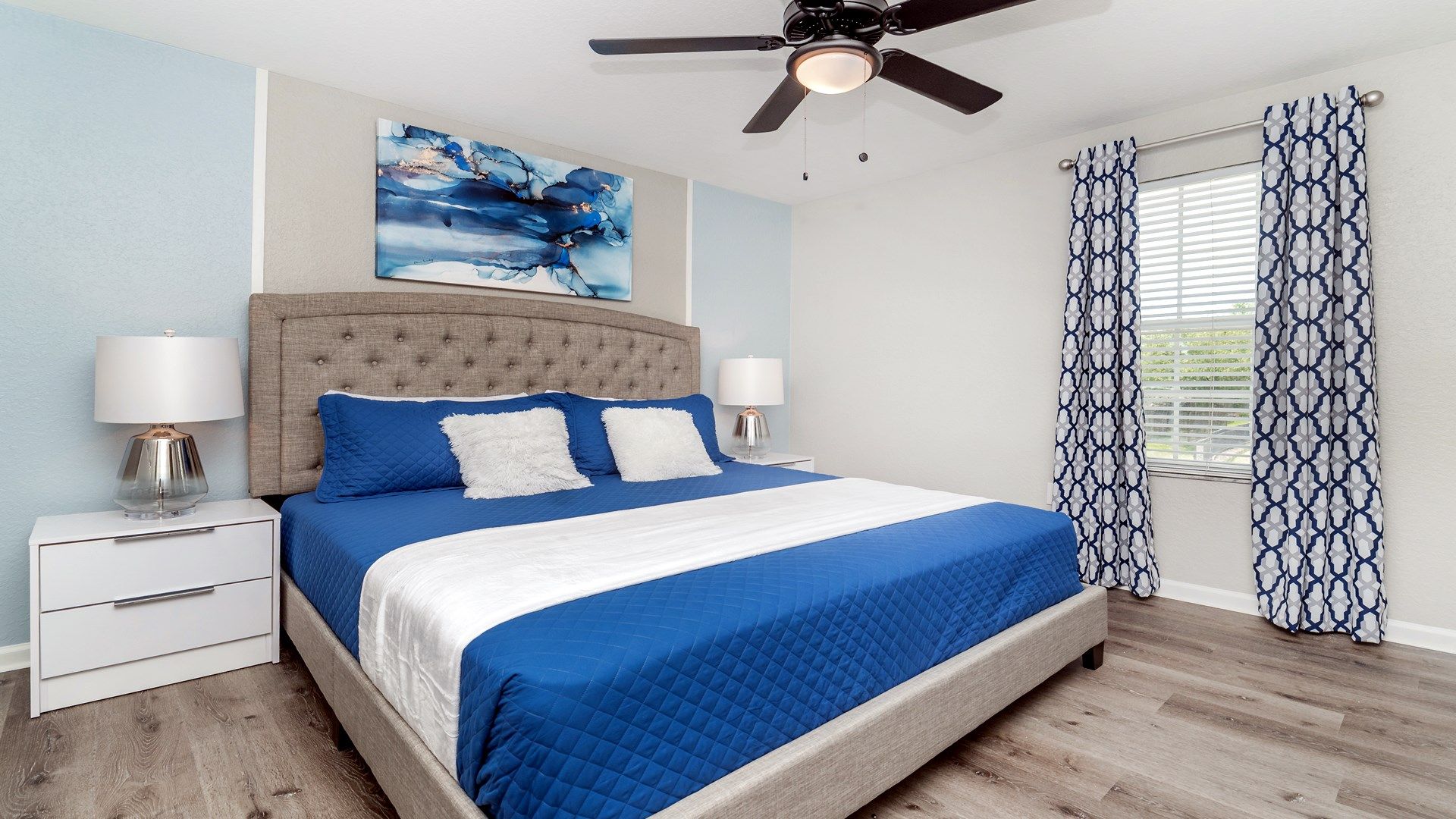 Vibrant bedroom with bold blue accents and dynamic abstract art.