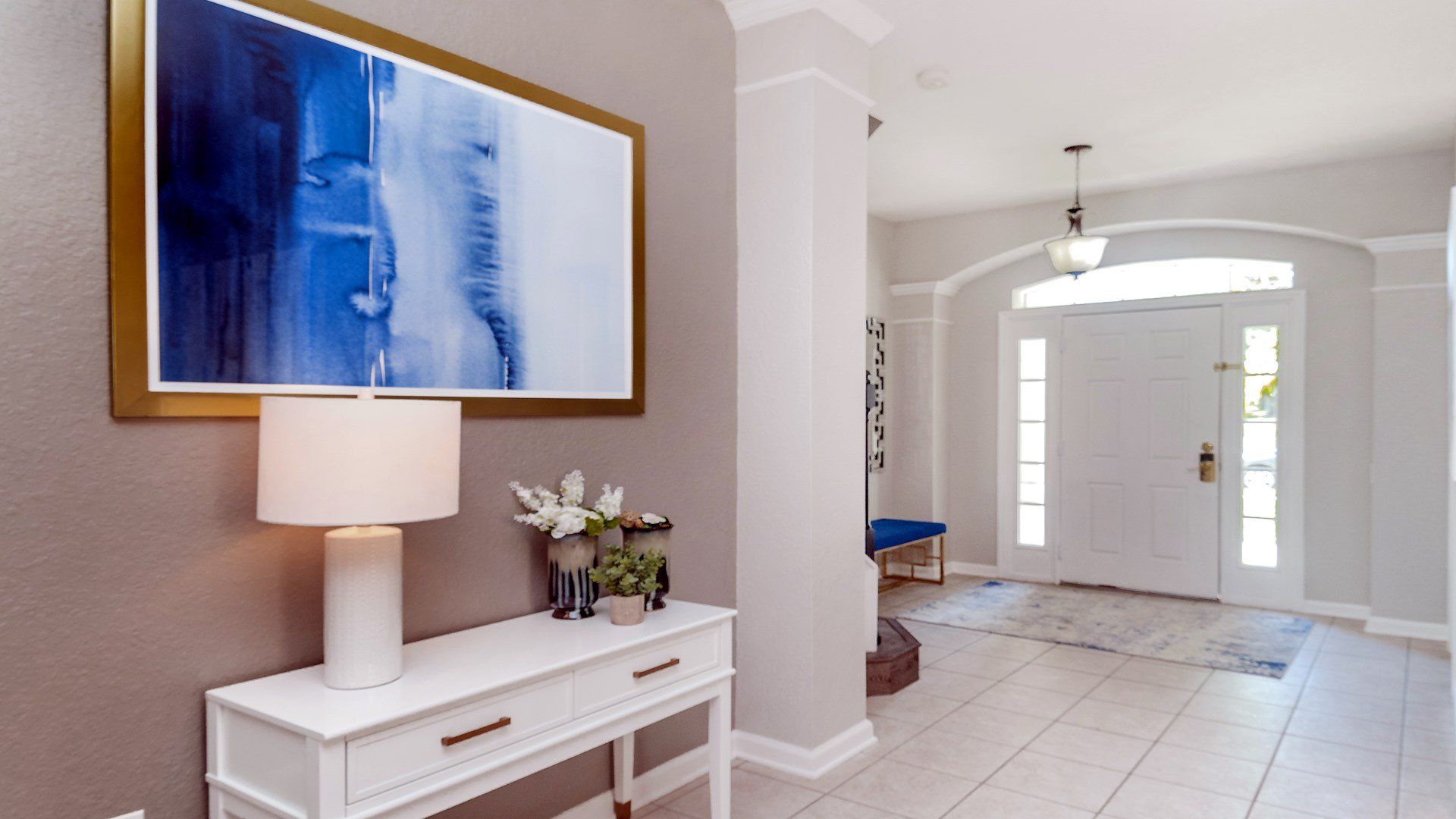 Stylish entryway with chic decor and a serene blue art piece.