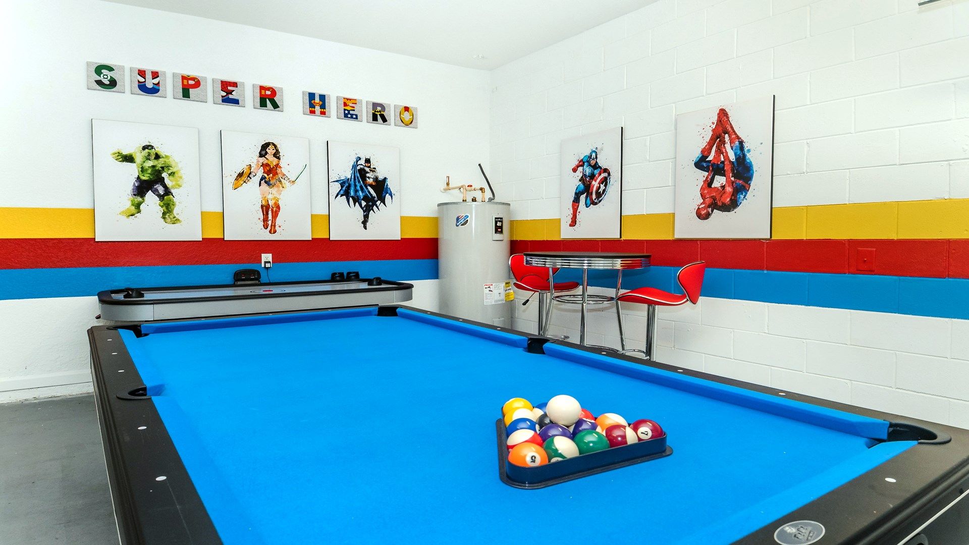Colorful game room with superhero art and a vibrant blue pool table.