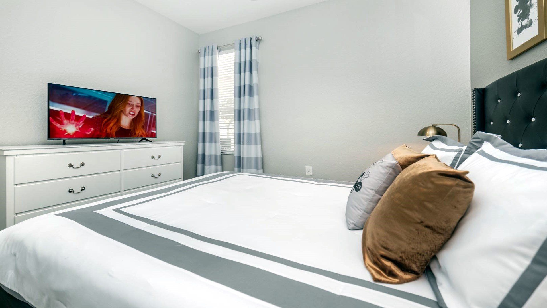 Sophisticated bedroom with plush bedding and a large entertainment setup.