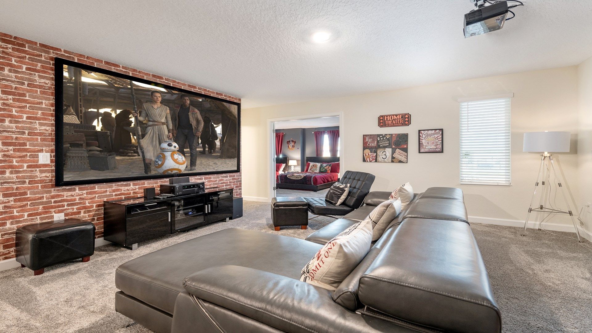 Cozy home theater with brick accent wall, large screen, and plush seating.
