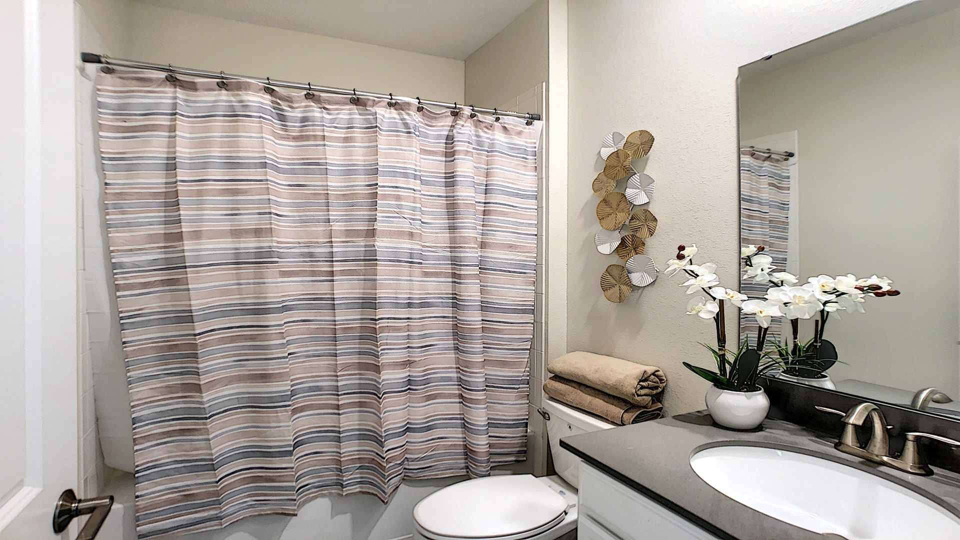 Stylish bathroom with a modern vanity, elegant décor, and a cozy shower-tub combo.