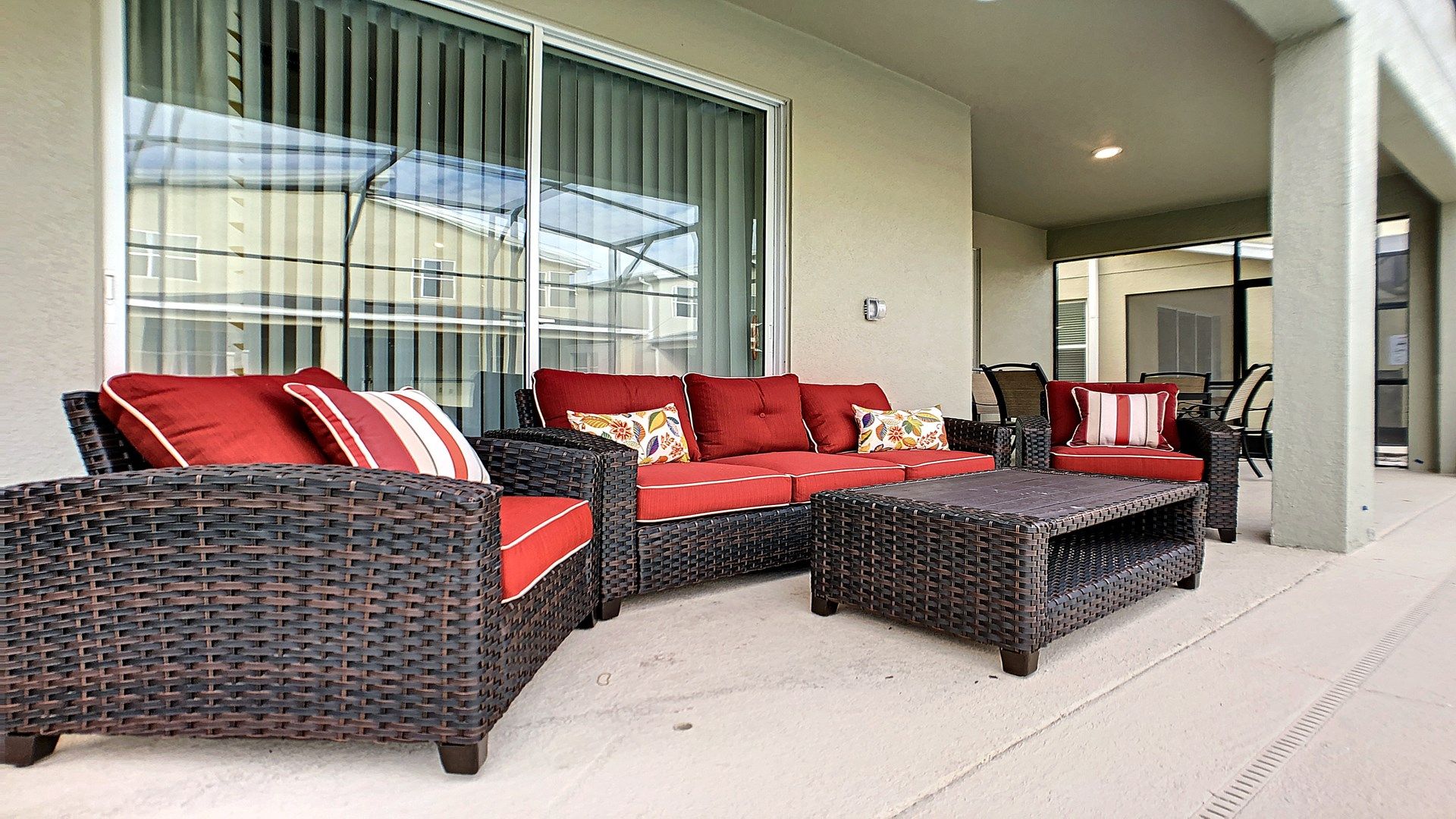 Relax in this stylish covered patio with cozy wicker seating and vibrant decor.