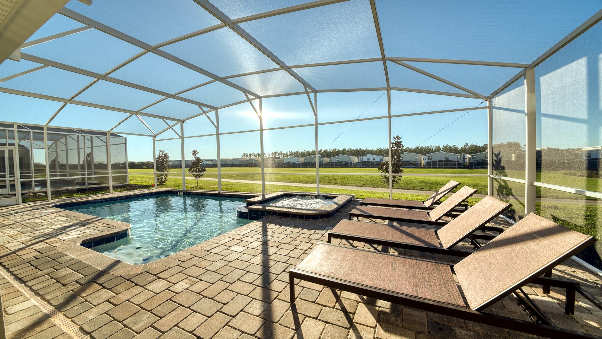 Screened private pool and spa with sunny patio and lounge chairs.