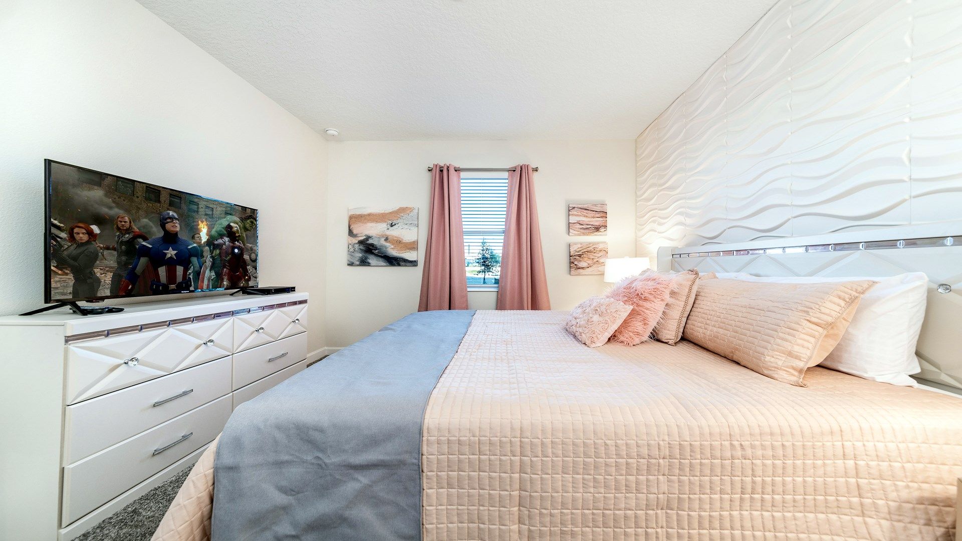 Elegant bedroom with soft pink accents, textured wall, and TV.