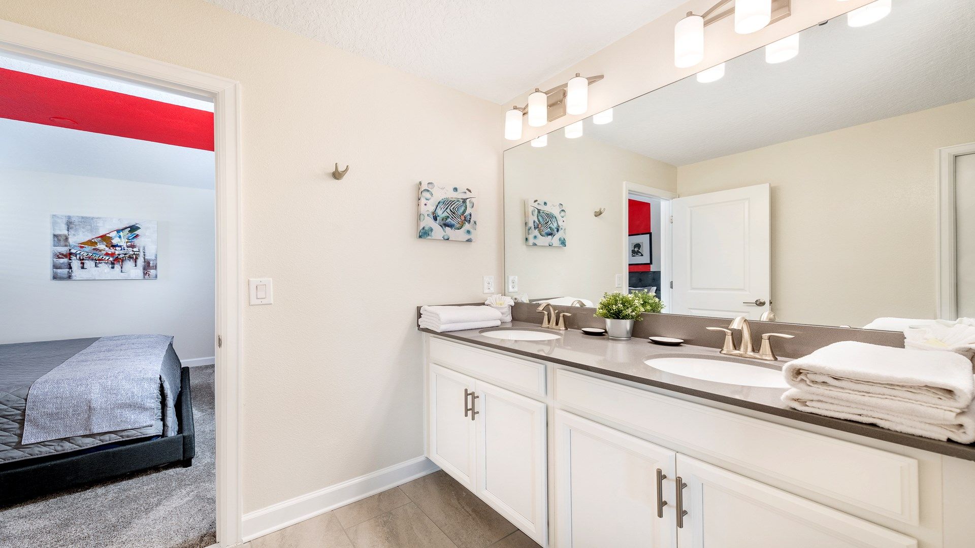 Sleek and spacious bathroom with vibrant art and a glimpse into a bold bedroom.