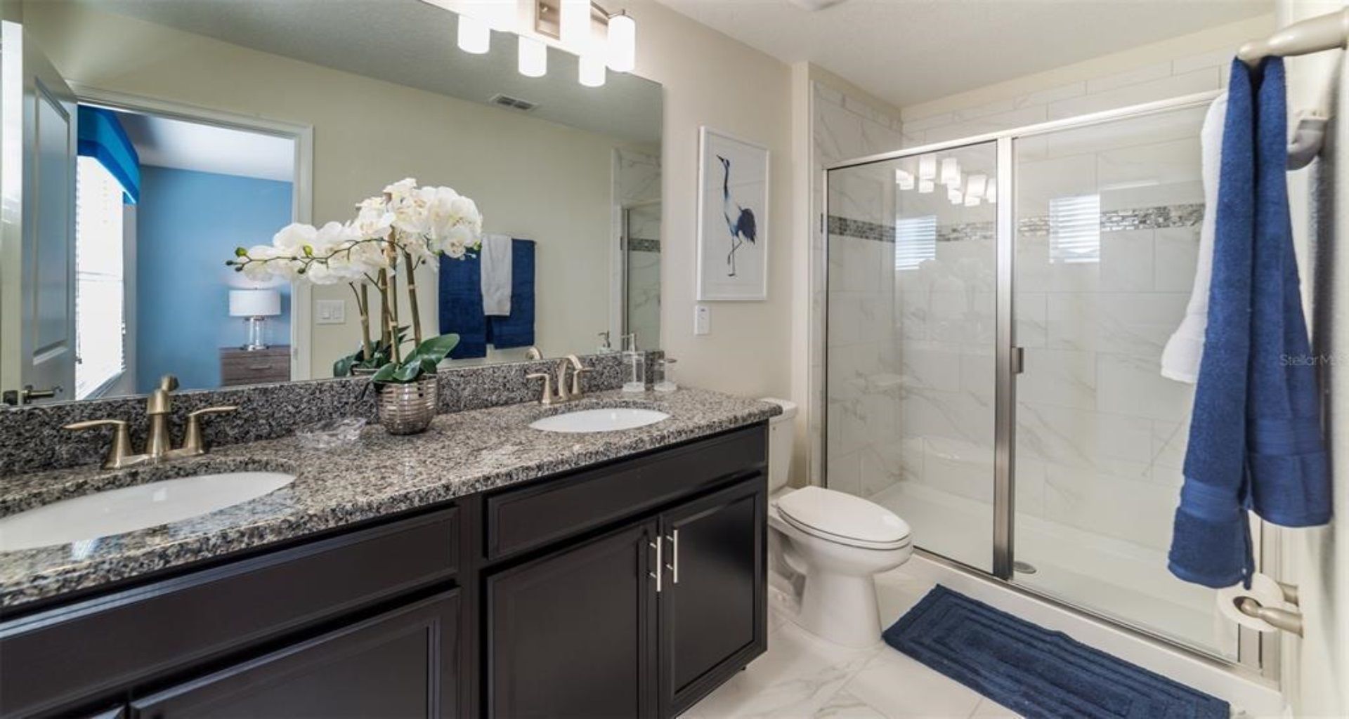 Elegant double vanity with granite counters and spa-style walk-in shower.