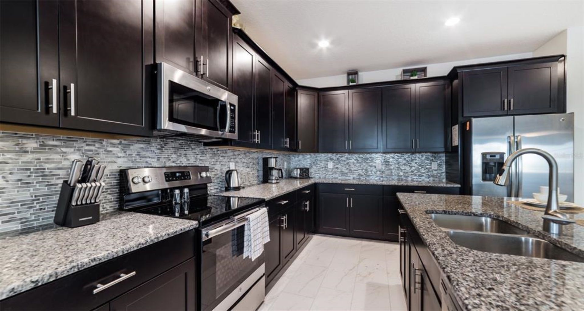 Sleek chef’s kitchen with granite counters, stainless steel appliances, and dark cabinetry.