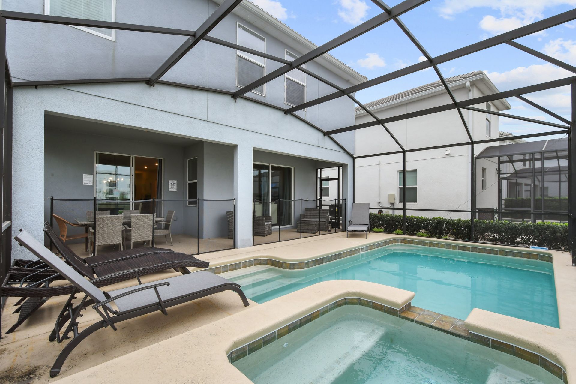 Relaxing screened pool and spa with sun loungers and covered outdoor dining area.