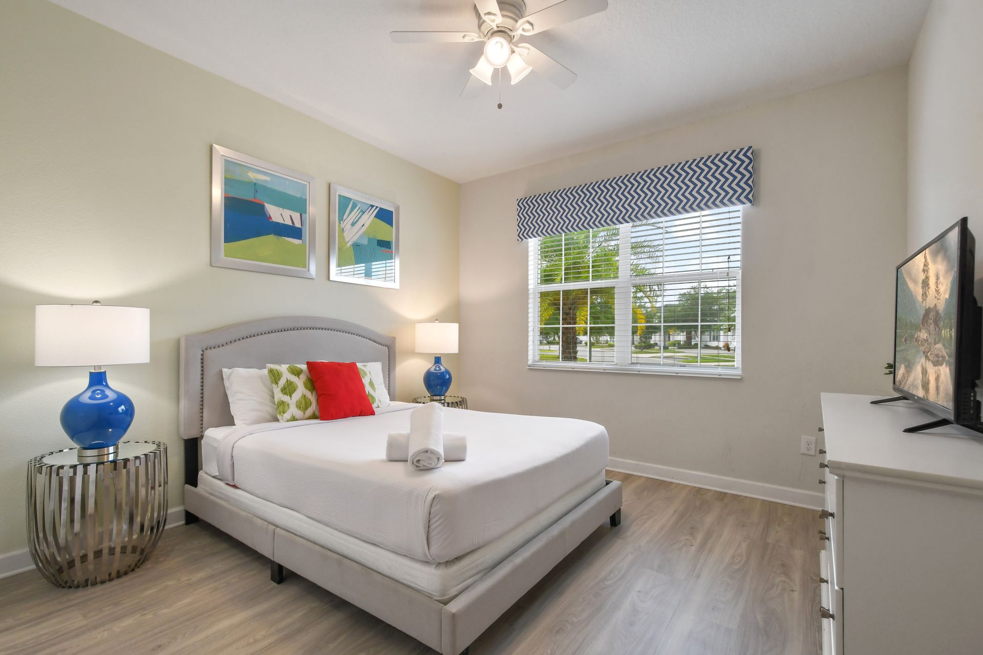 Vibrant bedroom with natural light, bold accents, and a smart TV for relaxing.