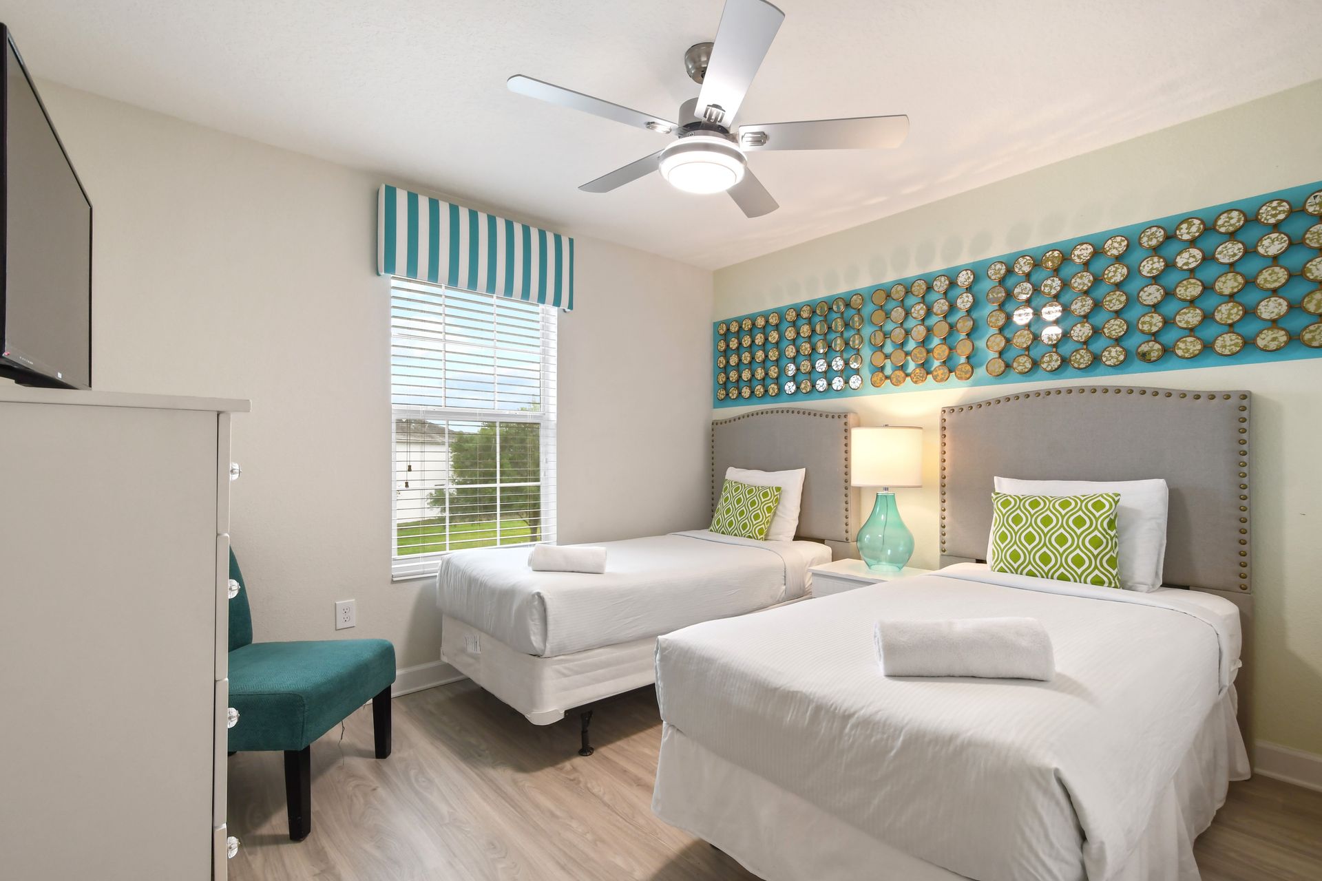 Stylish twin bedroom with playful decor, bold patterns, and a flat-screen TV.