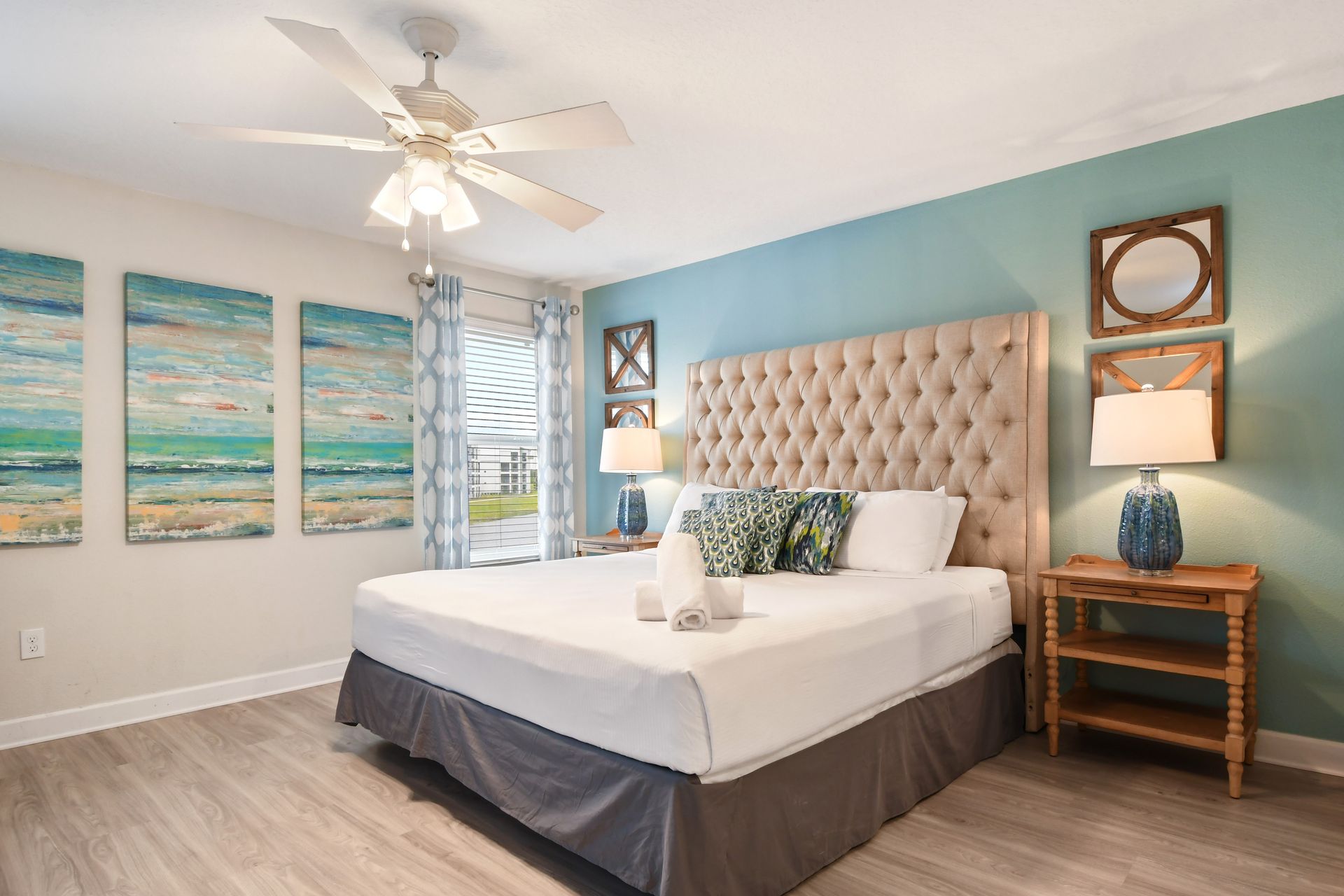 Coastal-inspired bedroom with king bed, bold artwork, and a tufted headboard.
