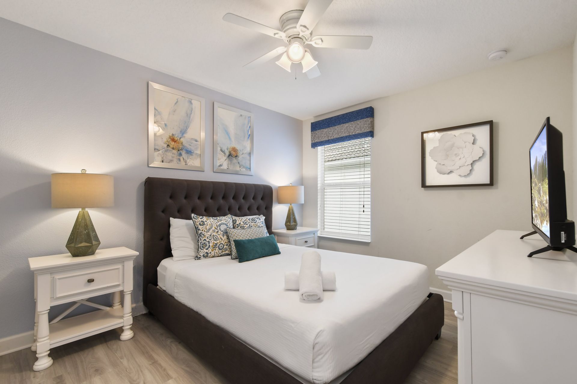Charming guest bedroom with plush headboard, soft lighting, and a sleek smart TV.