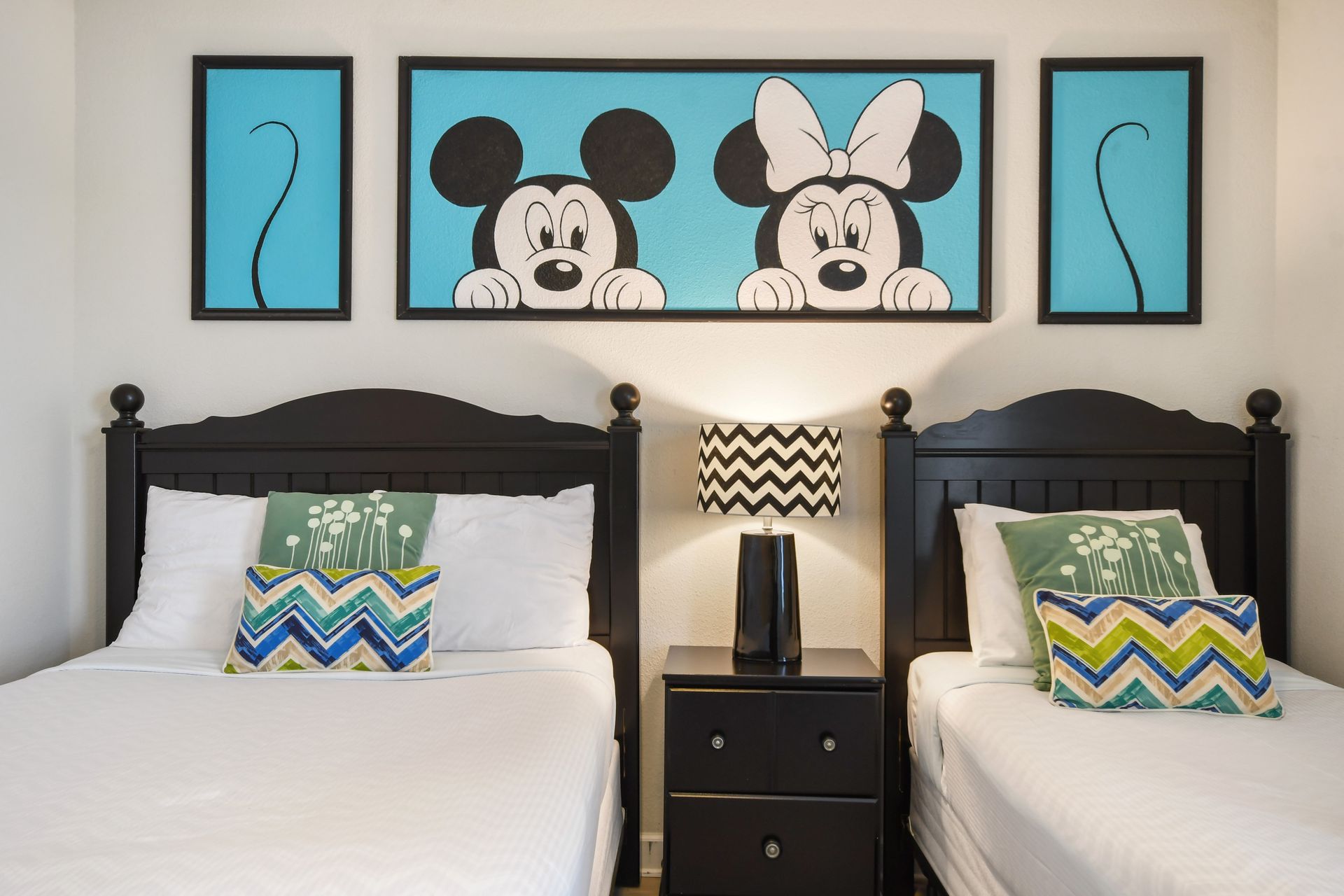 Whimsical twin room with character art, bold patterns, and cozy black bed frames.