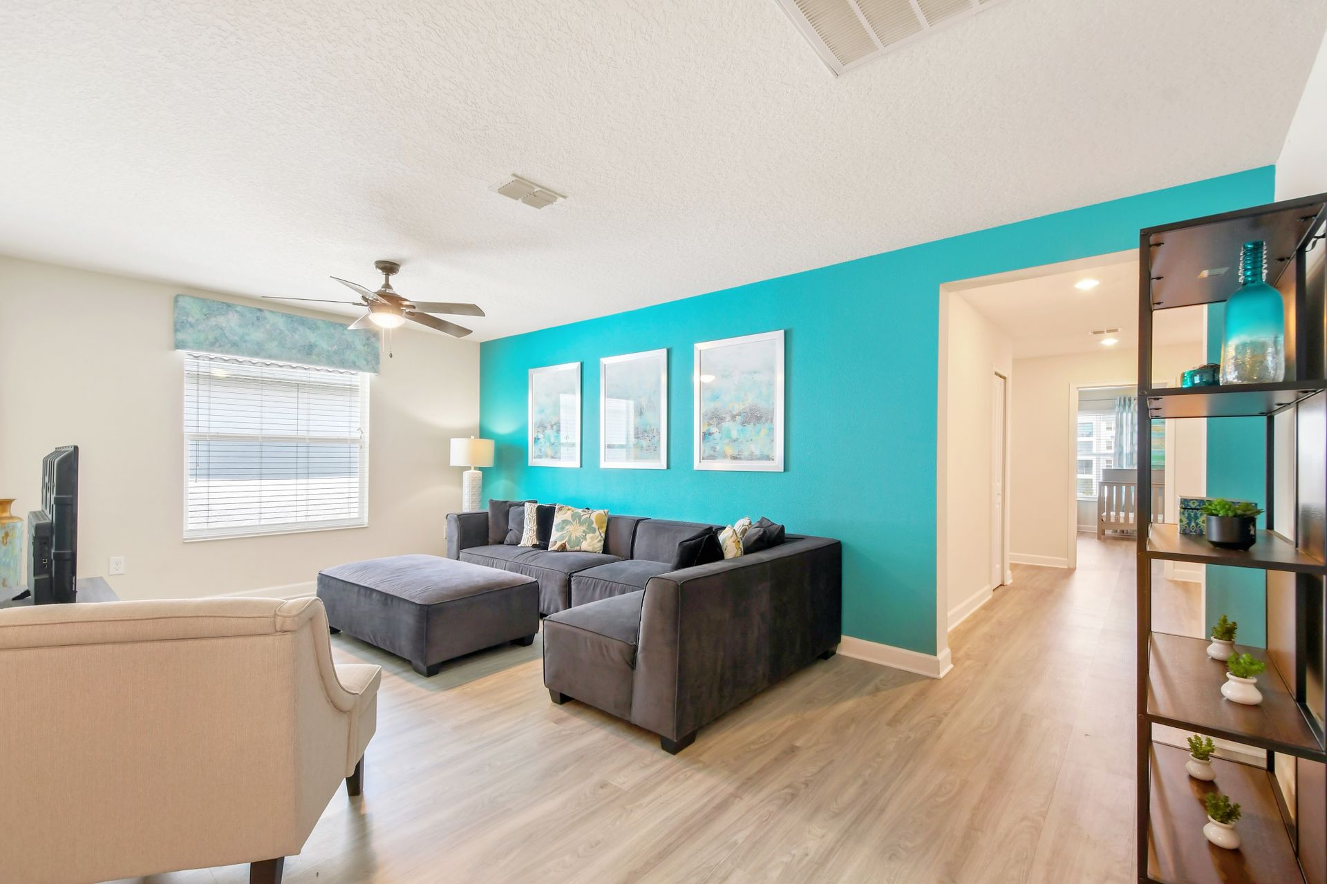 Bright upstairs retreat with teal accent wall, cozy sectional, and spacious layout.