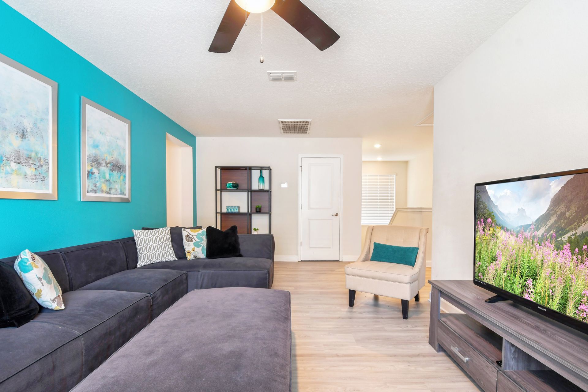 Colorful upstairs lounge with cozy sectional, smart TV, and bright, modern decor.
