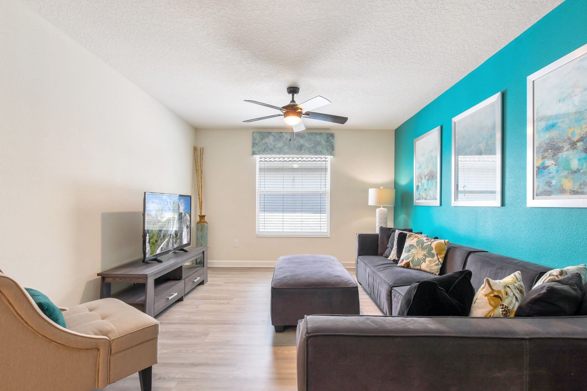 Cheerful upstairs media room with large sectional, bright teal accent wall, and TV.