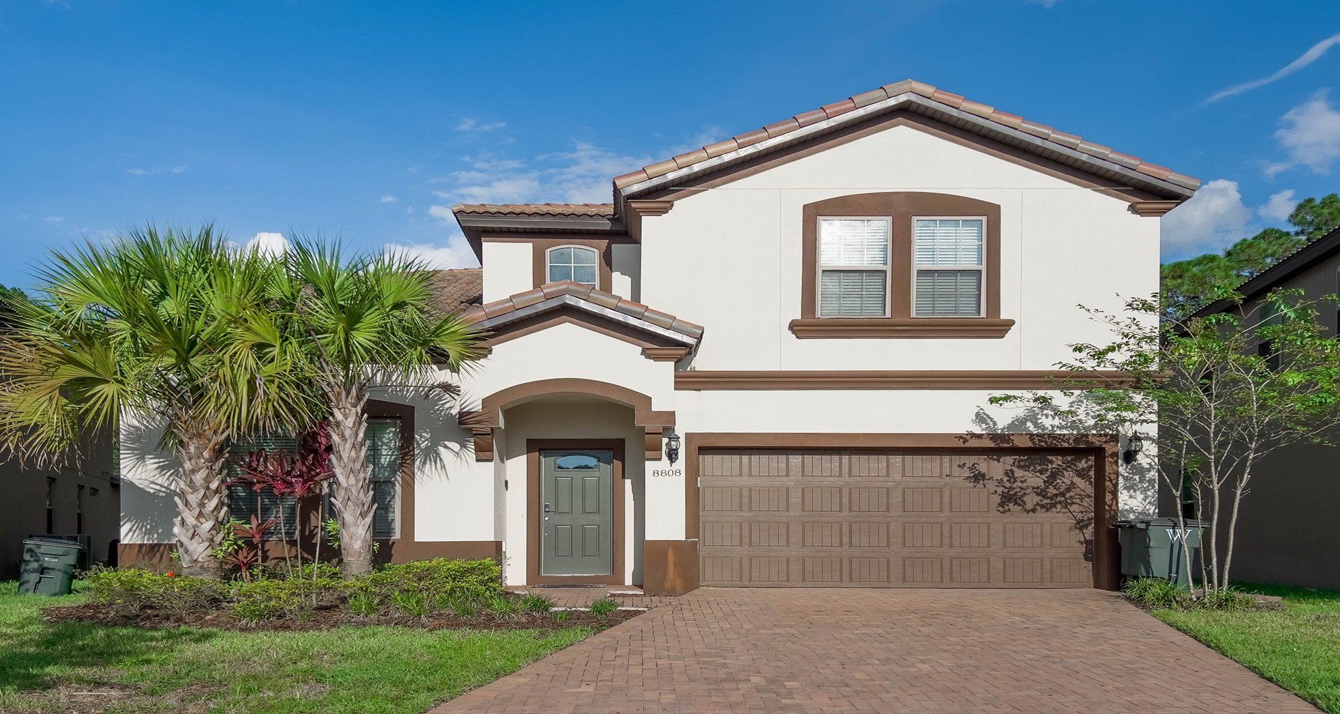 Modern two-story villa with tropical landscaping and spacious driveway parking.