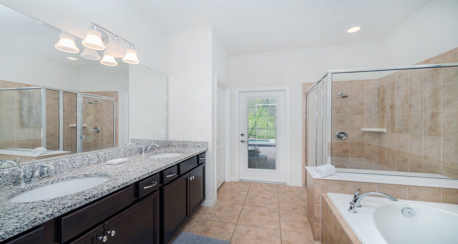 Luxurious bath with granite vanities, soaking tub, walk-in shower, and pool access.