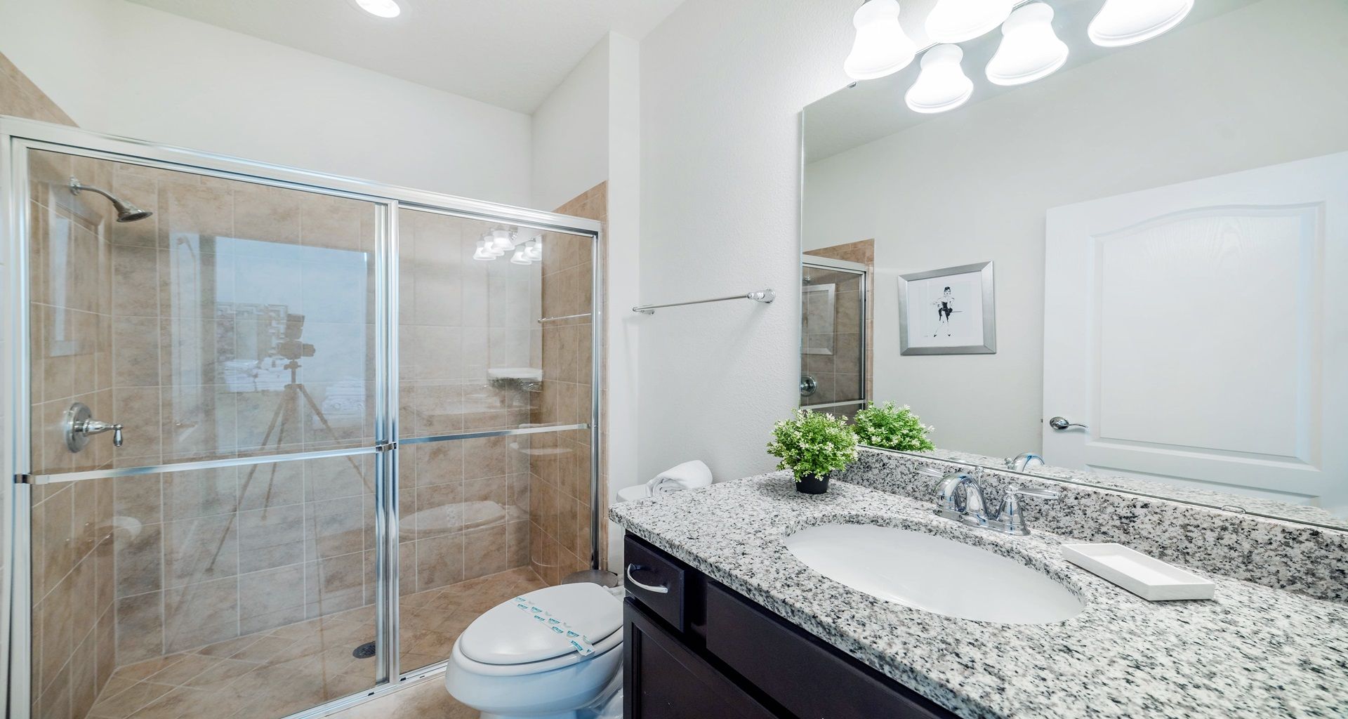 Elegant bathroom with granite countertop, glass walk-in shower, and modern flair.