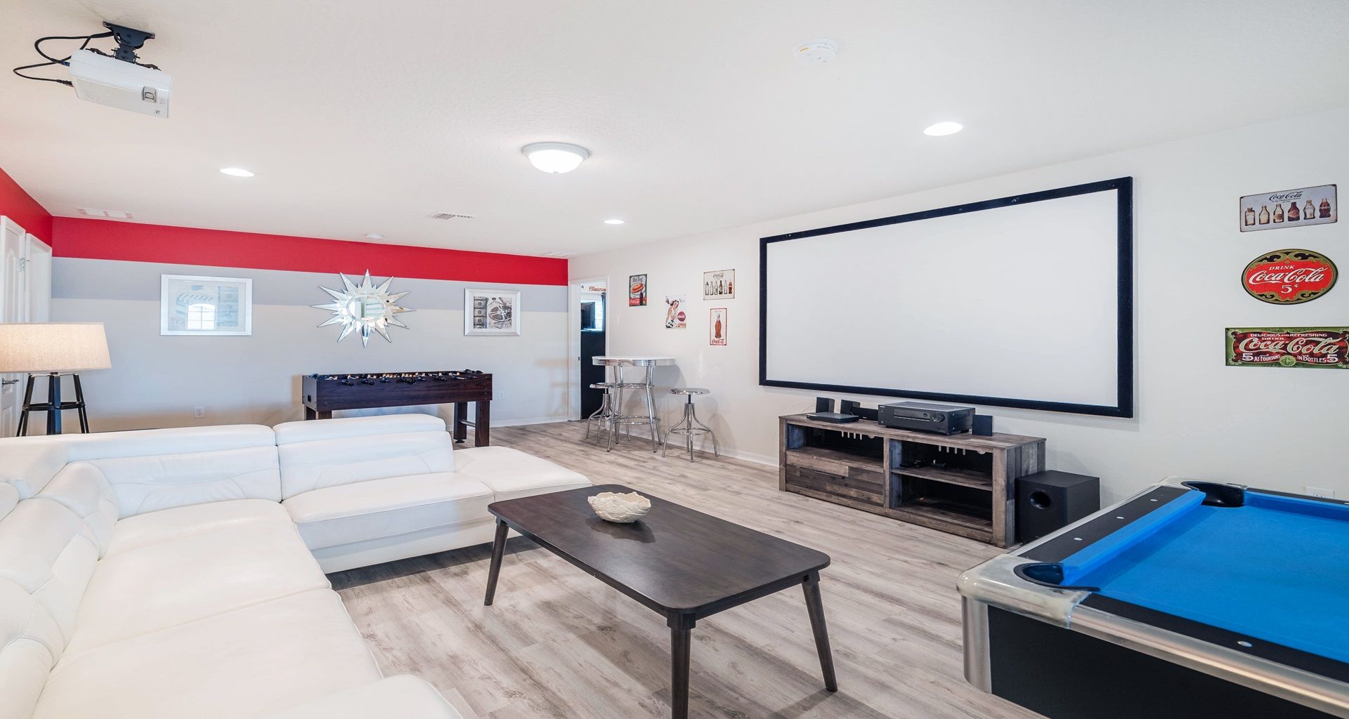 Entertainment room with pool, foosball, projector screen, and vintage decor.