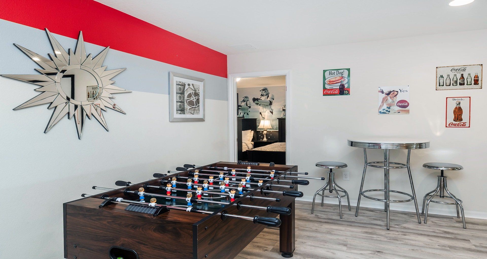 Retro-style game nook with foosball, bar seating, and vintage Coca-Cola decor.
