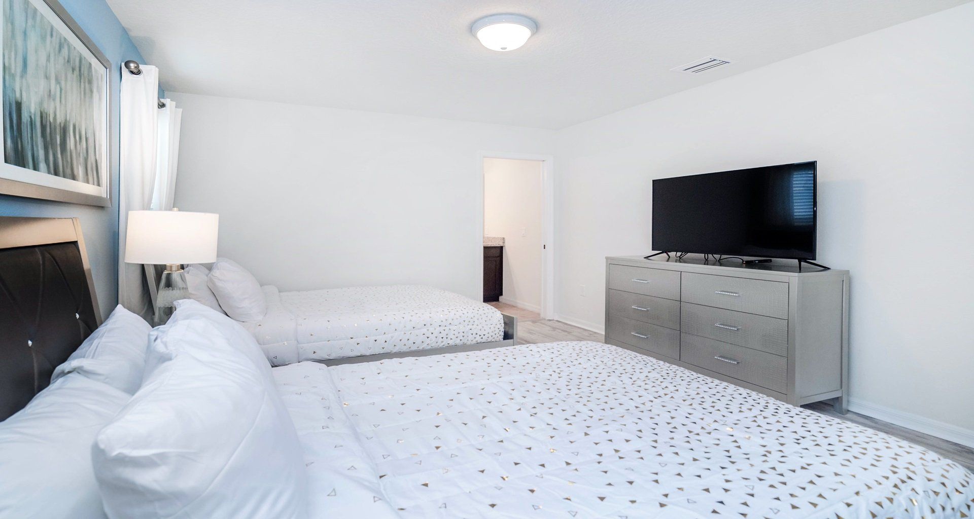 Spacious double queen room with TV, dresser, and stylish modern furnishings.