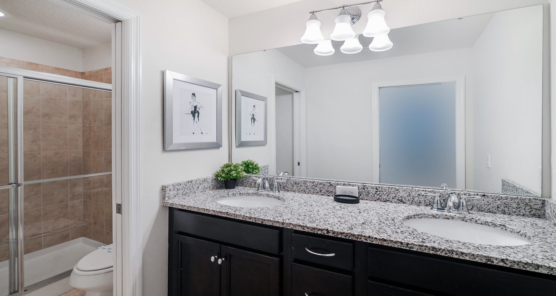 Modern bathroom with dual granite sinks, walk-in shower, and elegant fixtures.