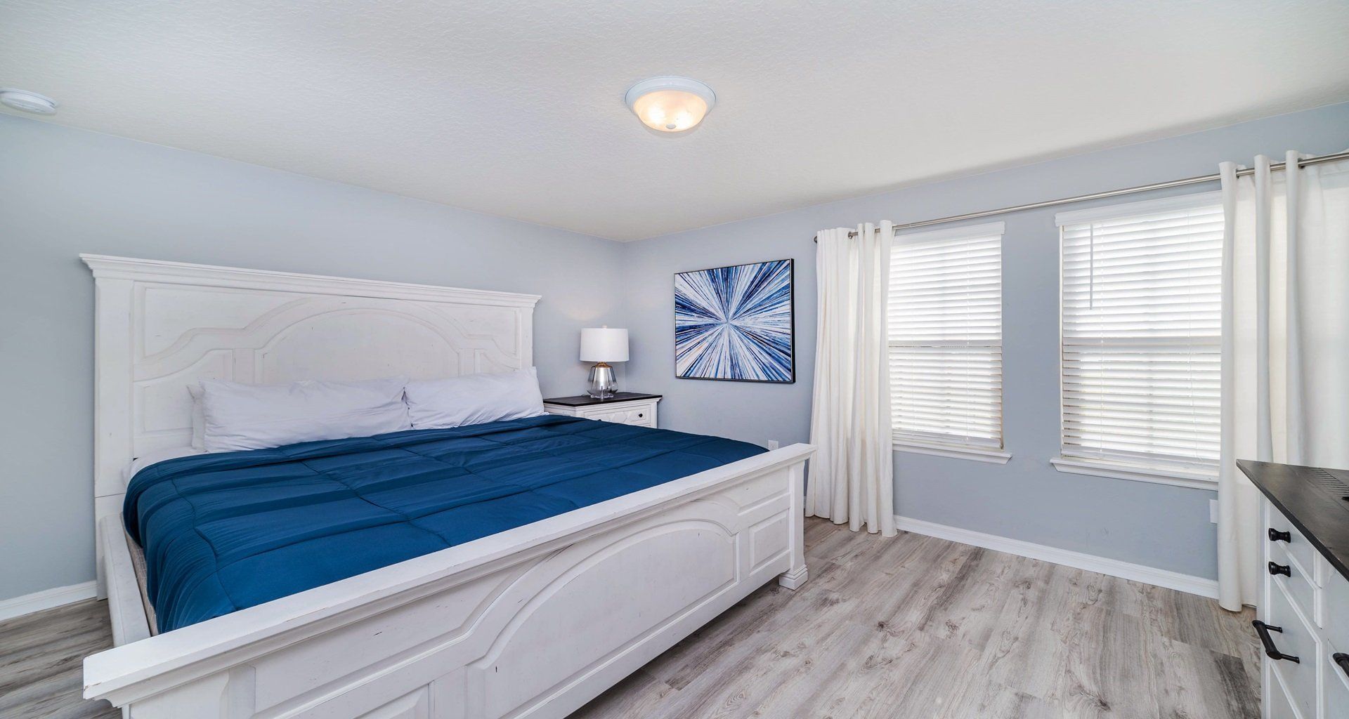 Tranquil king bedroom with soft light, coastal tones, and elegant wood finishes.