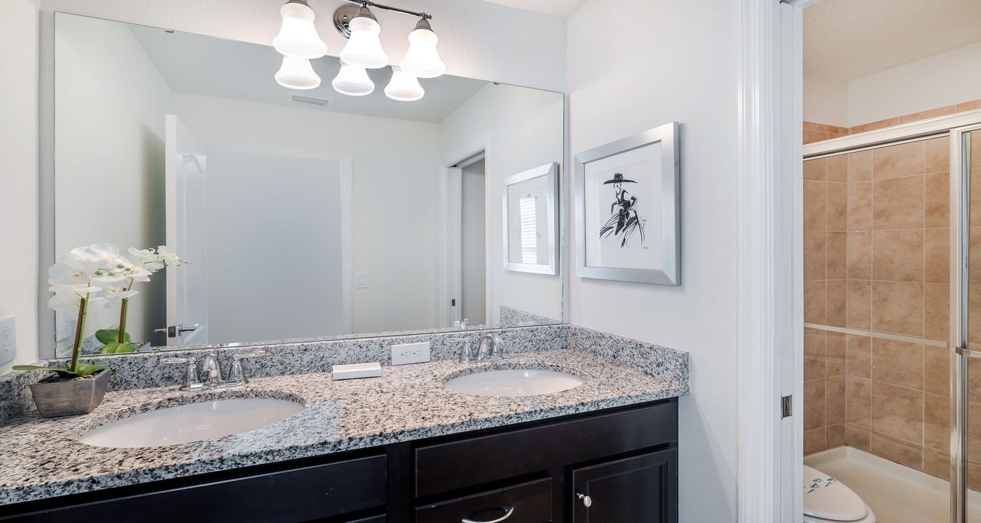 Chic bathroom with granite dual sinks, glass shower, and soft elegant lighting.