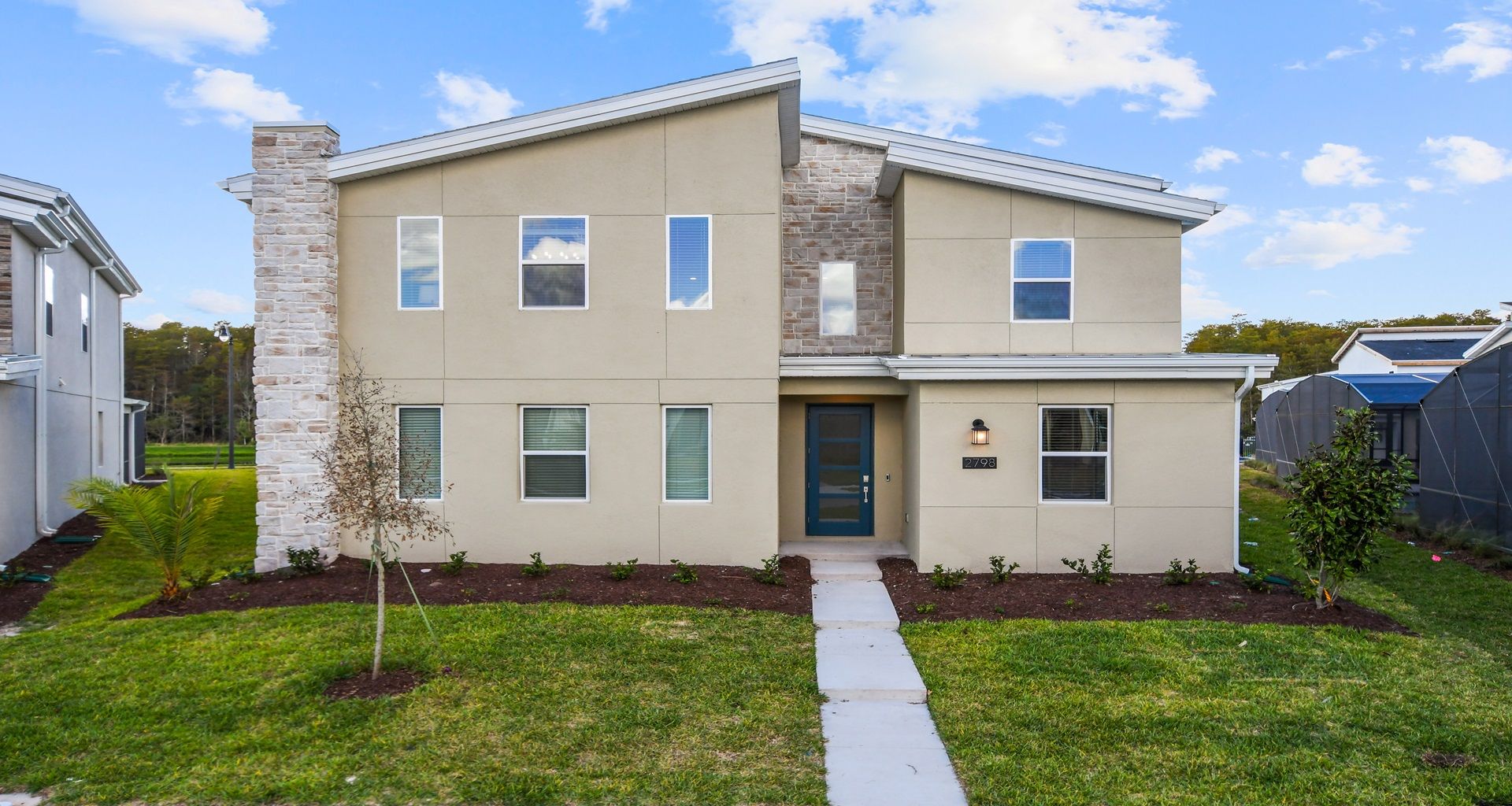 Contemporary home design featuring a modern aesthetic with a touch of brick for a timeless charm, complemented by lush greenery.